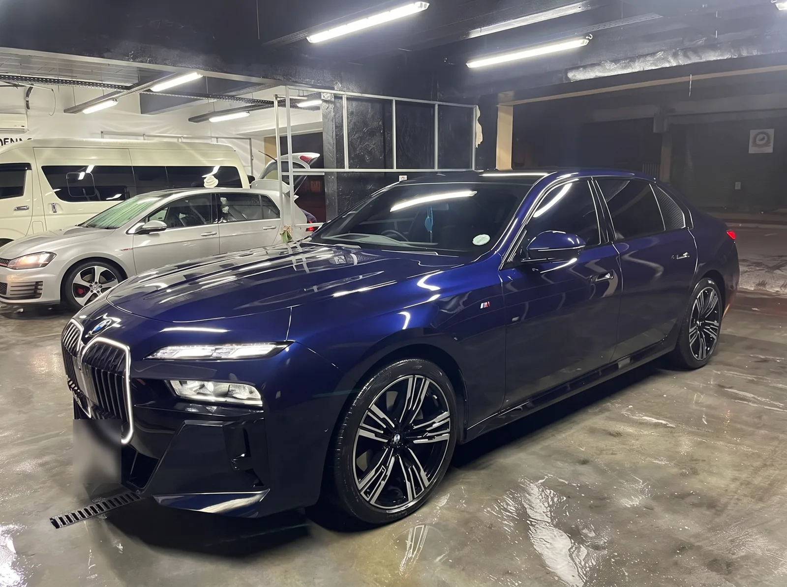A dark blue BMW 740Li sedan, side view