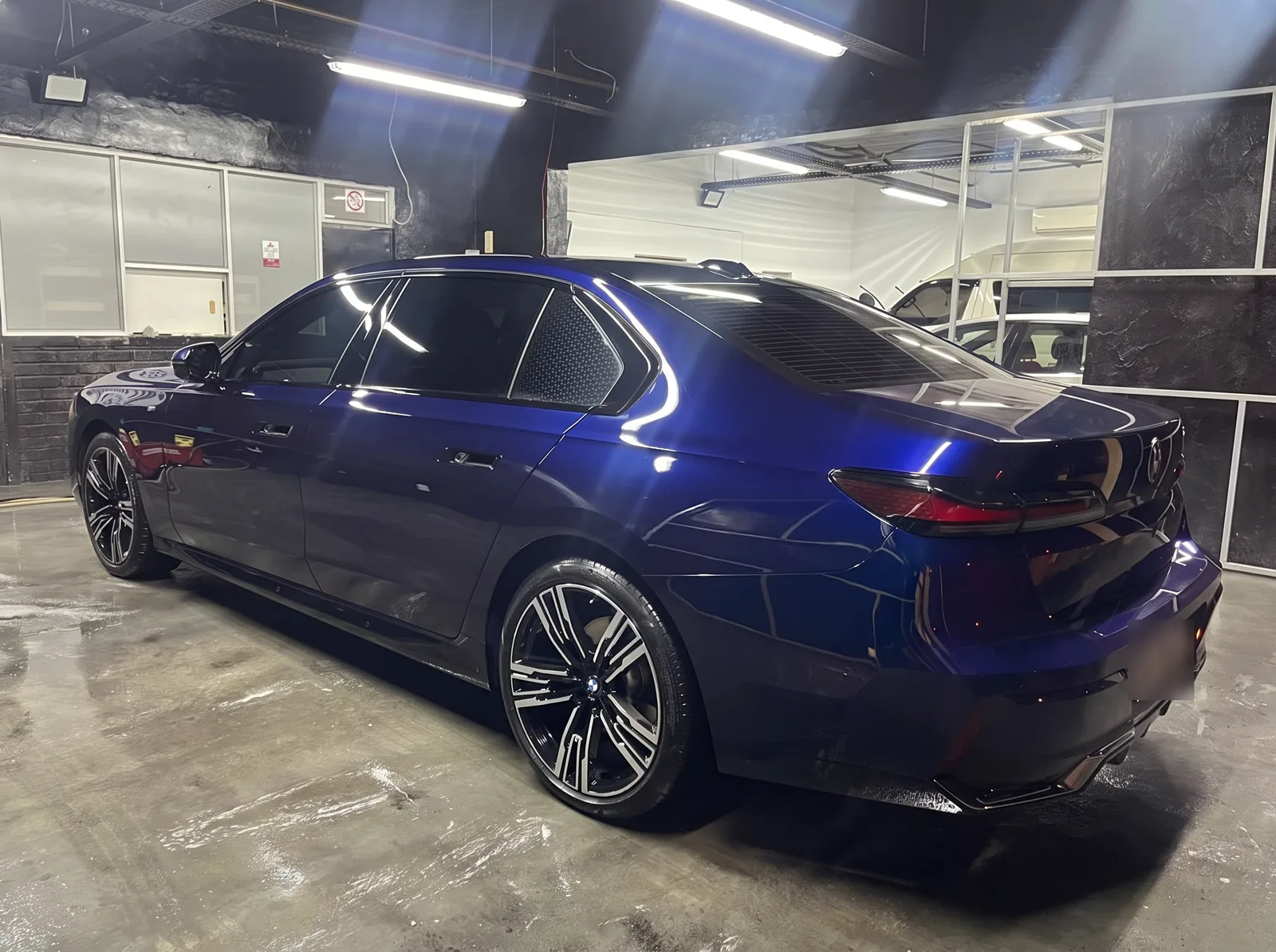 A dark blue BMW 740Li sedan, rear view