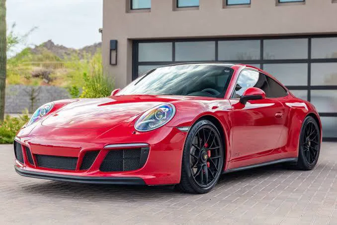 A red Porsche 911 in front of a modern garage
