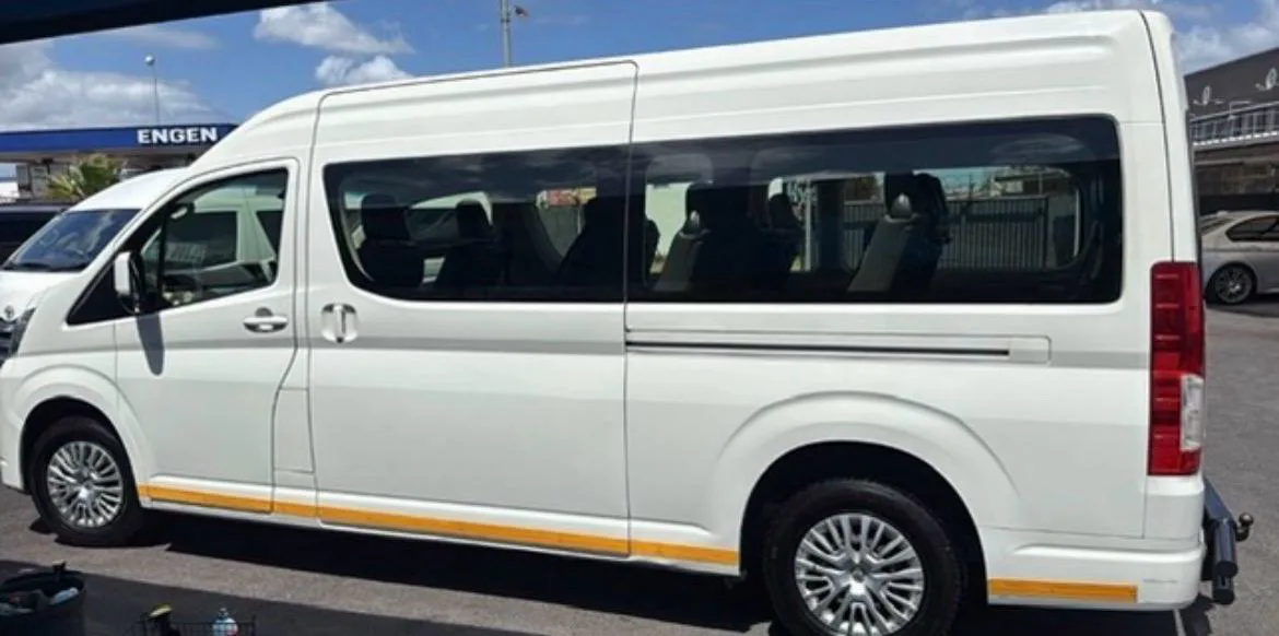 A white Toyota Quantum high-roof minibus, side view