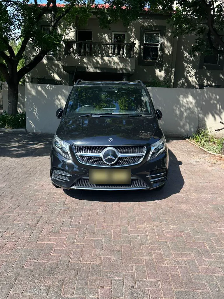 A black Mercedes-Benz V-Class, head-on, in a paved driveway