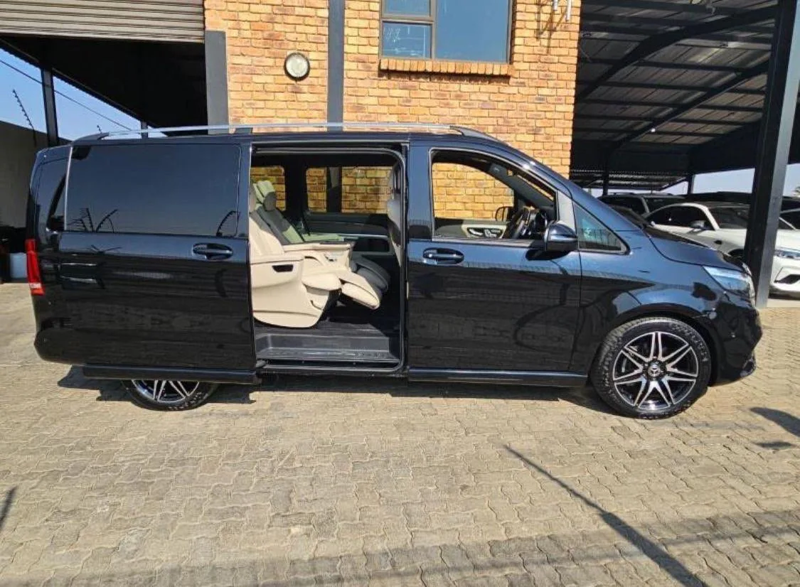 A black Mercedes-Benz V-Class with the sliding door open, showing cream leather seats